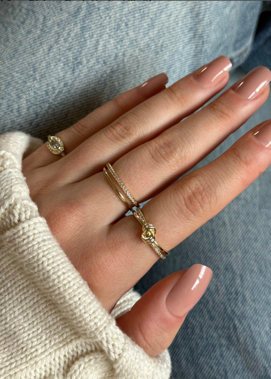 Hand wearing two gold rings with a blurred background