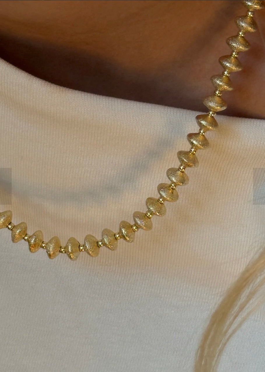 Gold necklace on a white fabric background