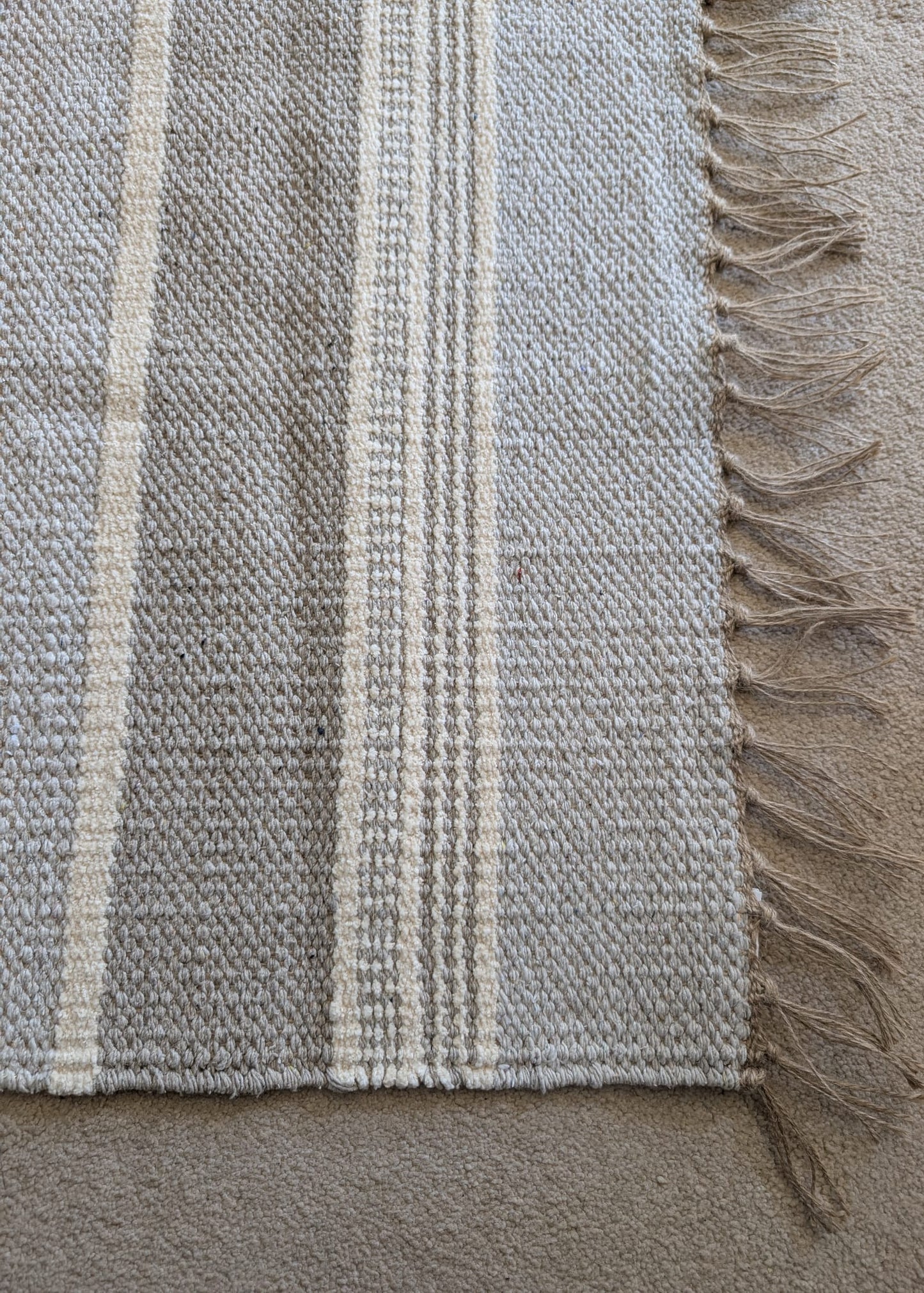 Textured fabric with plaid pattern and frayed edge on a neutral background