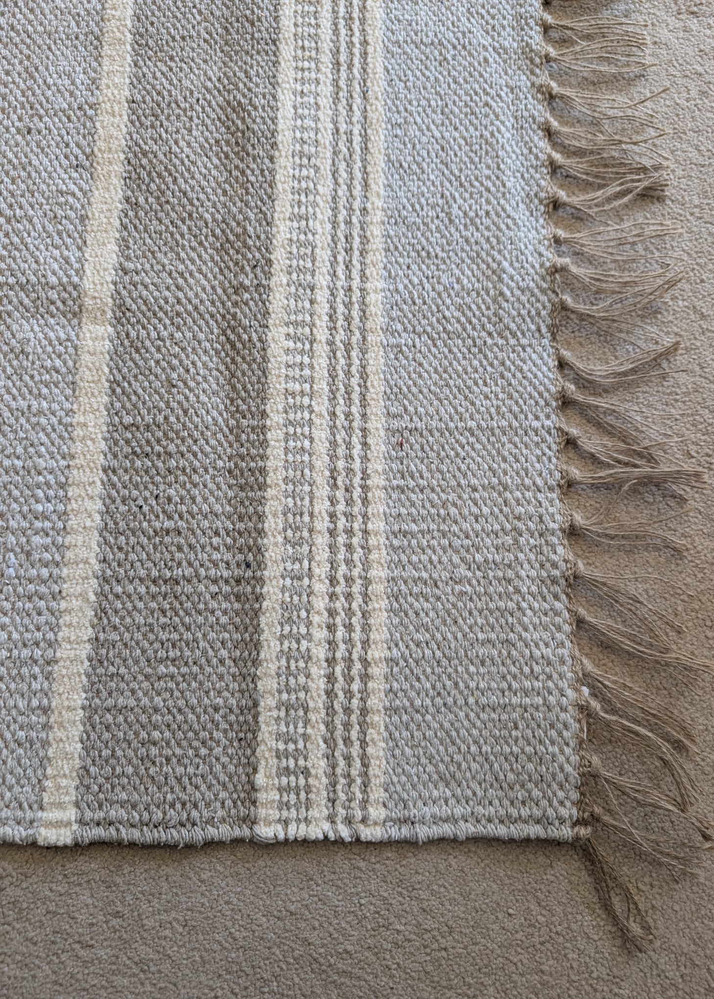 Textured fabric with plaid pattern and frayed edge on a neutral background