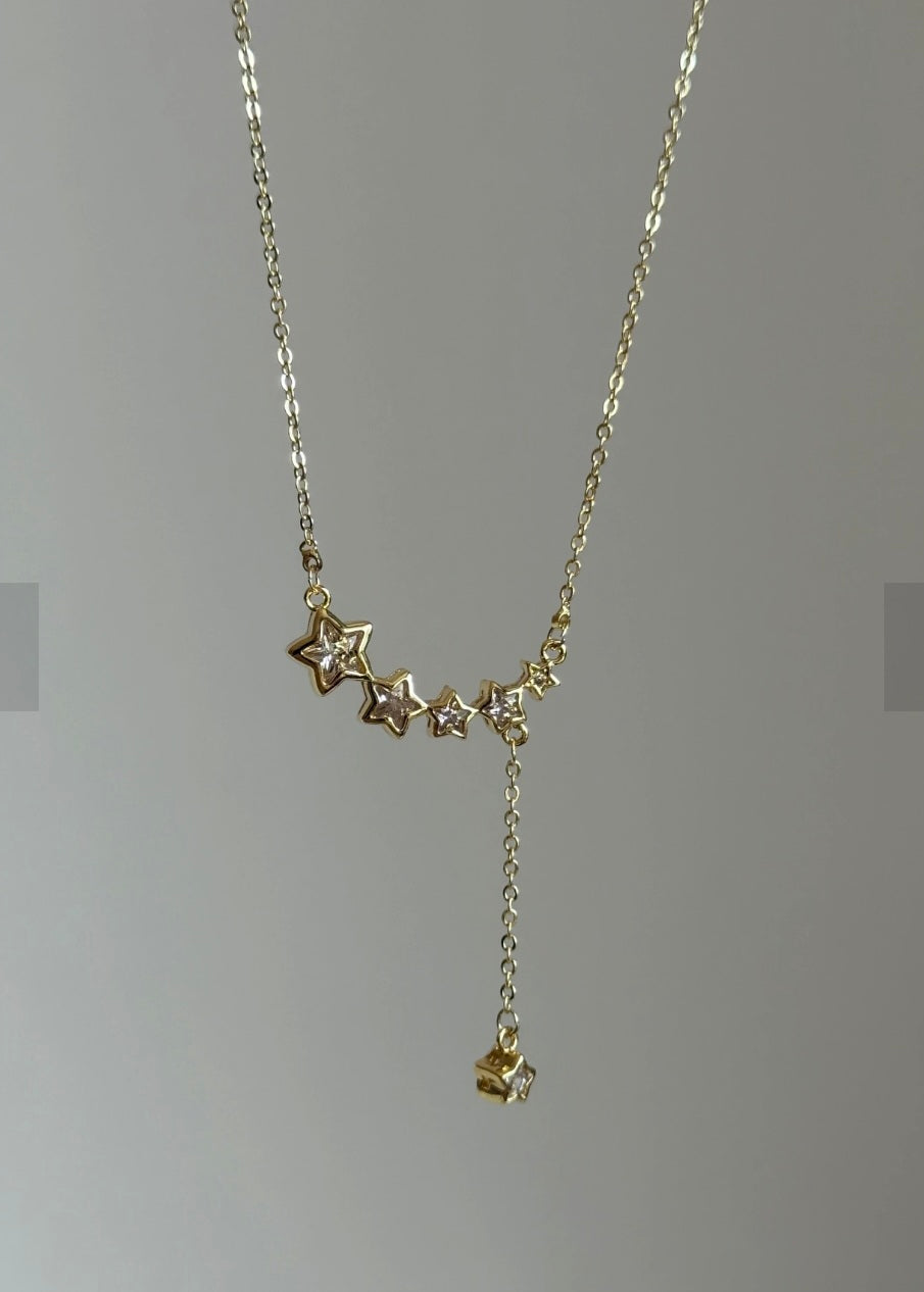 Gold star necklace on a gray background