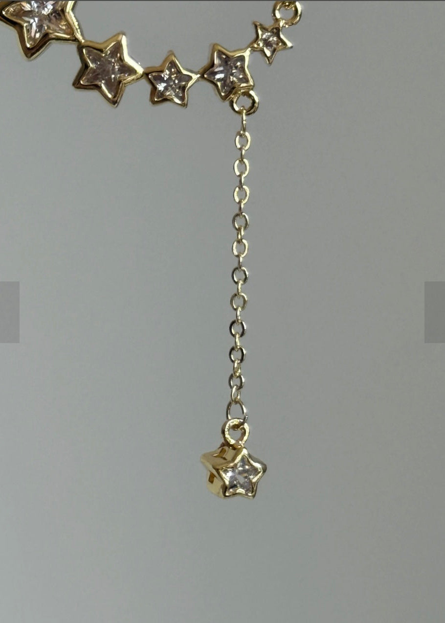 Gold necklace with star-shaped pendants on a gray background