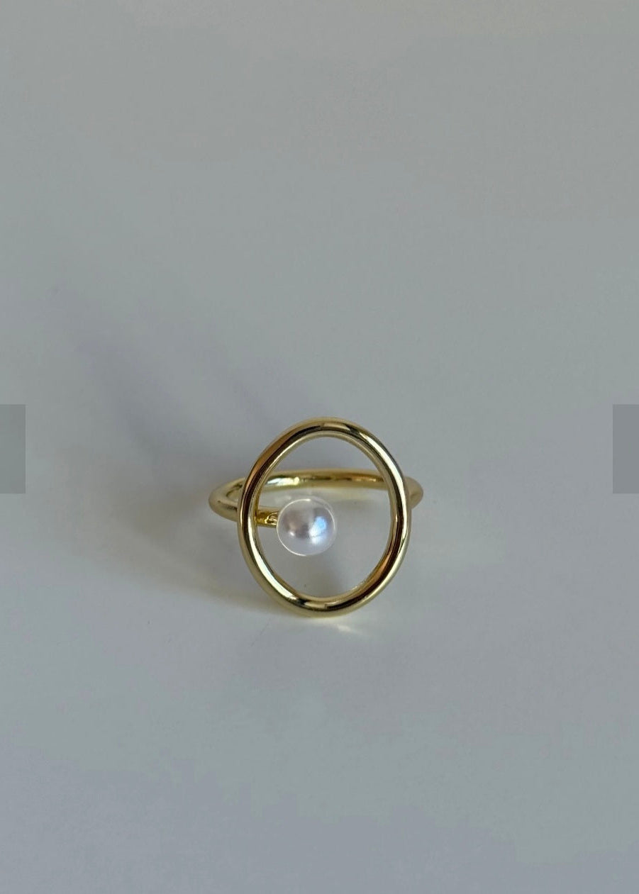 Gold ring with a pearl on a light gray background