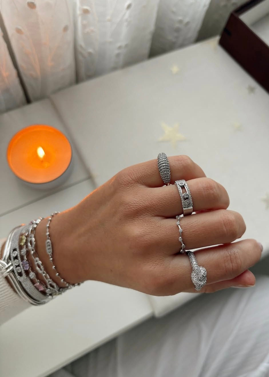 Hand wearing multiple silver rings with a candle in the background